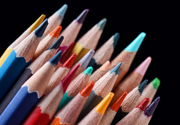 A group of colored pencils are lined up against a black background.