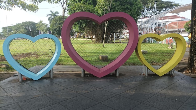 A group of colorful heart shaped objects sit on a sidewalk.