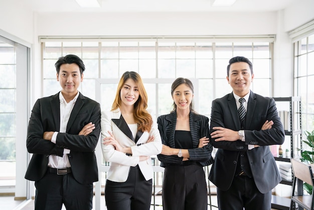 A group of confident Asian businessmen and businesswomen colleagues standing in the office and looking at the camera Unity and diversity of position executive manager and employee teamwork concept