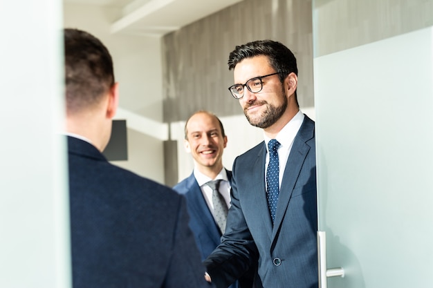 Group of confident business people greeting with a handshake at business meeting in modern office