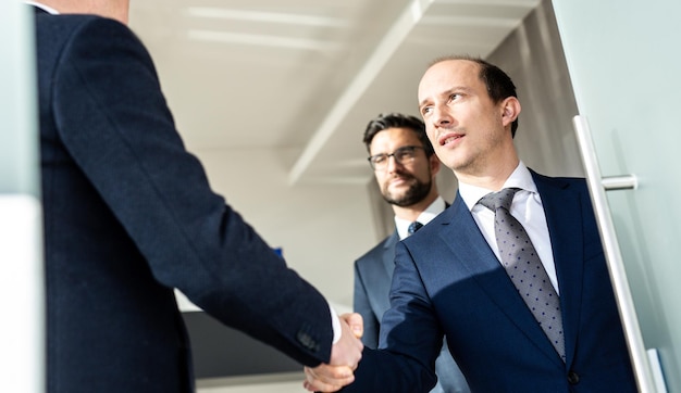 Group of confident business people greeting with a handshake at business meeting in modern office or