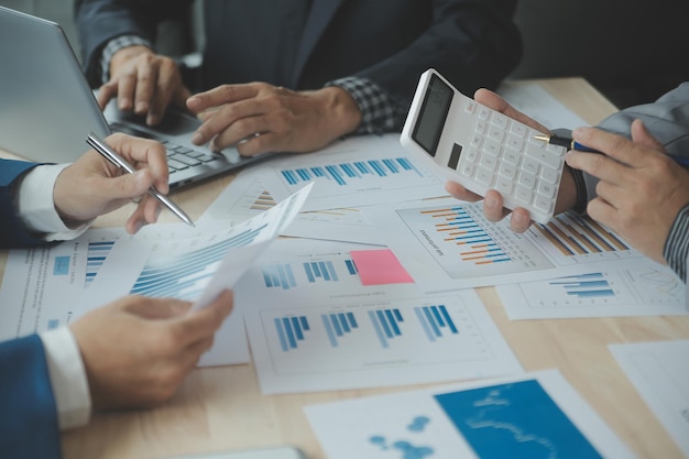 Group of confident business people point to graphs and charts to analyze market data balance sheet account net profit to plan new sales strategies to increase production capacity