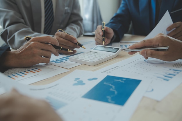 Group of confident business people point to graphs and charts to analyze market data balance sheet account net profit to plan new sales strategies to increase production capacity