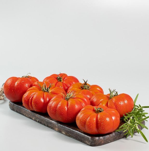 A group of Costoluto big tomatoes and rosemary on a white background space for text