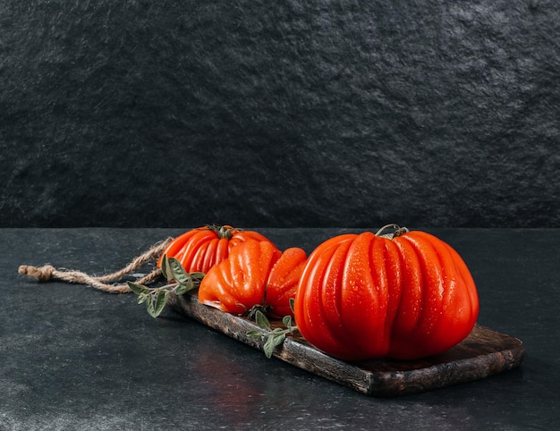 A group of Costoluto big tomatoes with oregano on a grey background space for text