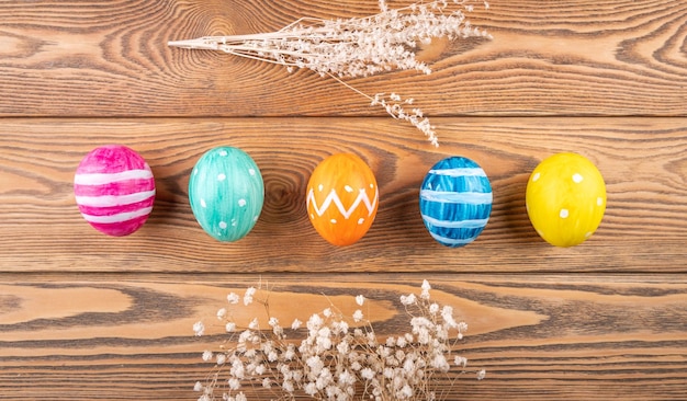 A group of cute colorful Easter eggs decorated with paints on a wooden background Top view