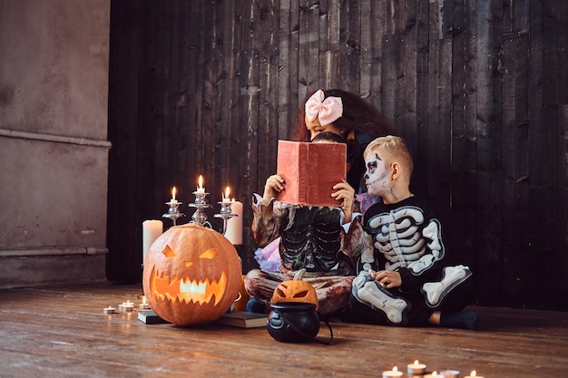 Group of cute multiracial kids in scary costumes reading horror stories in an old house, during Halloween party. Halloween concept.