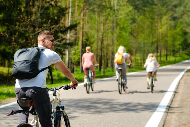 A group of cyclists with backpacks ride bicycles on a forest road enjoying nature.