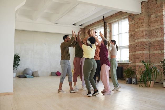 Photo group of dancers giving high five to each other during training in dance studio