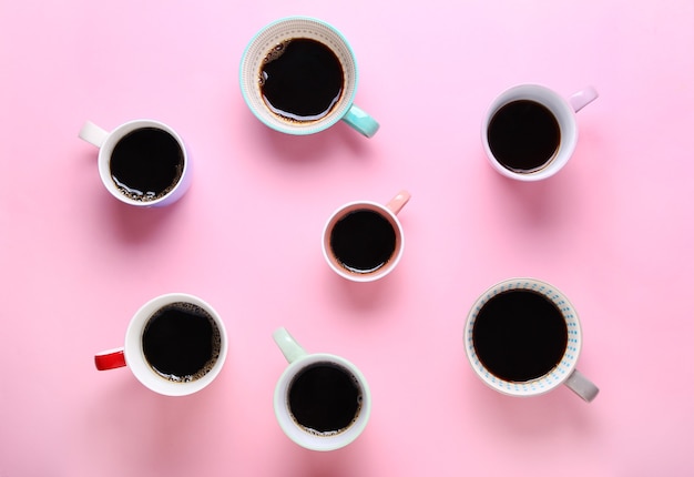 Group of different cups of coffee on pink background.