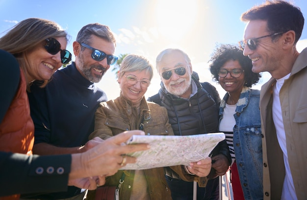 Group of diverse middleaged tourist people standing looking at travel map in hands