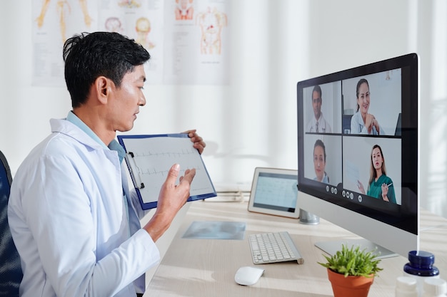 Group of doctors having online conference and discussing cardiogram of patient