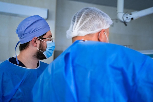 Group of doctors perform an operation to a patient Surgeons in medical uniform and masks working in the operating room