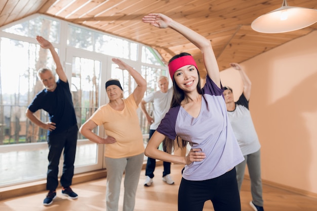 Group of elderly women and men doing therapeutic gymnastics.