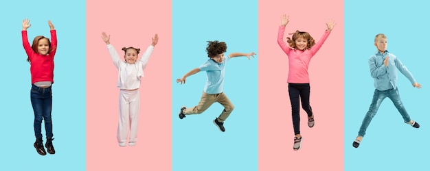 Group of elementary school kids or pupils jumping in colorful casual clothes on bicolored studio