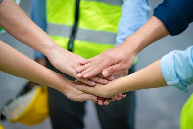 Group of engineers and workers join hands for teamwork in warehouse factory