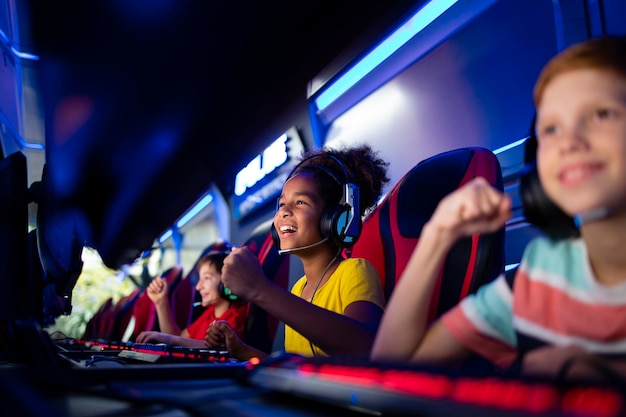 Group of excited children or professional gamers playing video games on computer in game room