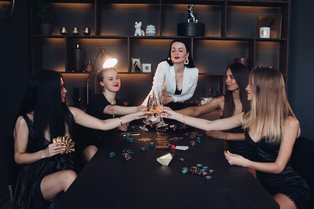 Group of fashion young sexy woman enjoying playing poker and drinking champagne