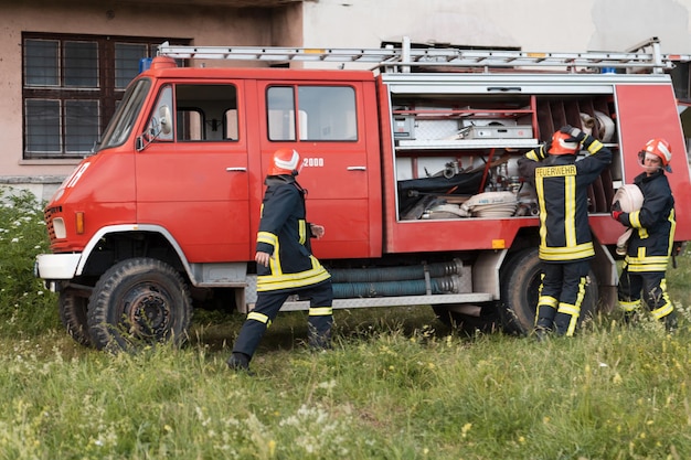 Group of fire fighters standing confident after a well done rescue operation. Firemen ready for emergency service. High quality photo