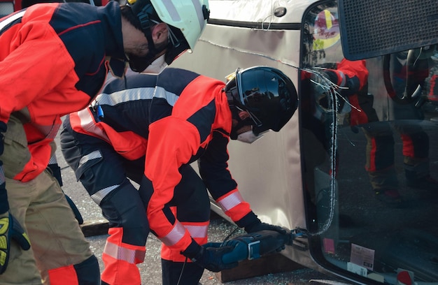 Group of firefighters wearing uniforms and helmets carry out a rescue in a car accident