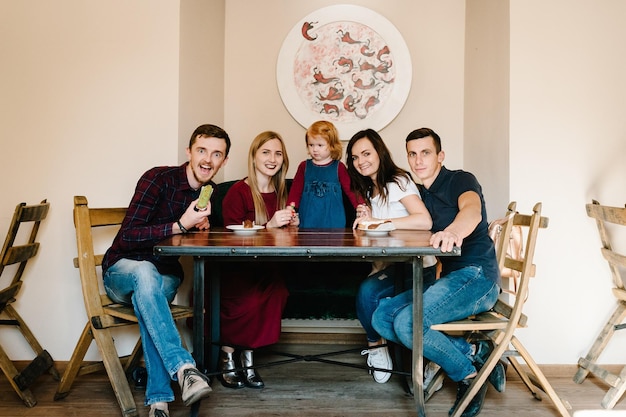 Group of five friends having fun a coffee together Two women and child and two men at cafe talking laughing and enjoying their time Celebrate Happy Day 8 March