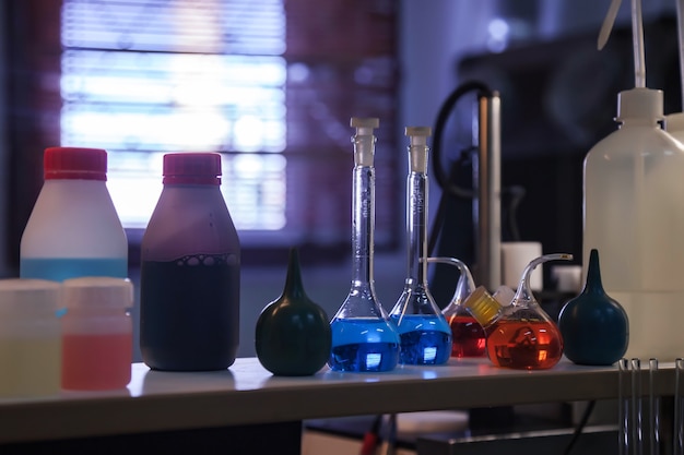 Group of flasks and test tubes in chemical laboratory. Reagents and samples acid suspensions on laboratory table for experiments. Various conical flasks with samples of different colors in interior