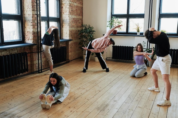 Group of flexible teenage performers doing warmup exercises before training