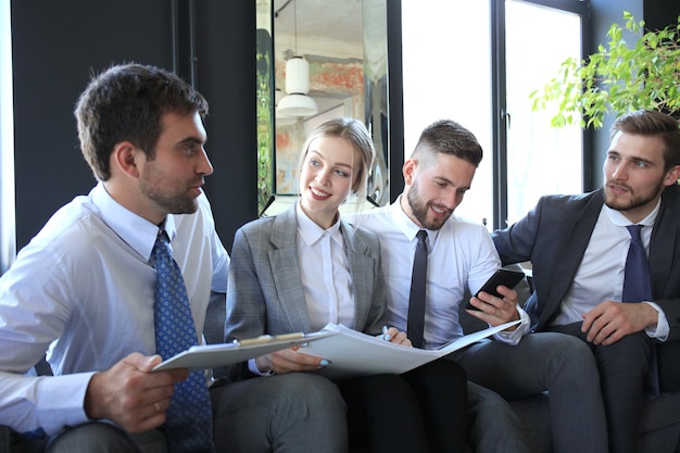 Group of four business people sitting on sofa. They couldn't be happier about working together.