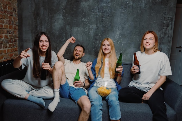 A group of four friends during the celebration of the victory of their favourite sports team at home on TV