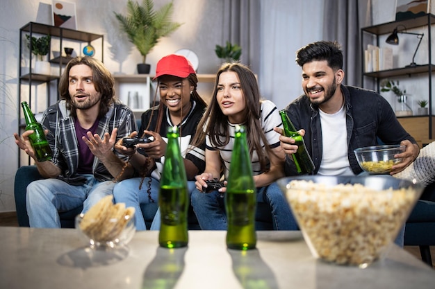 Group of four friends with joysticks playing video games