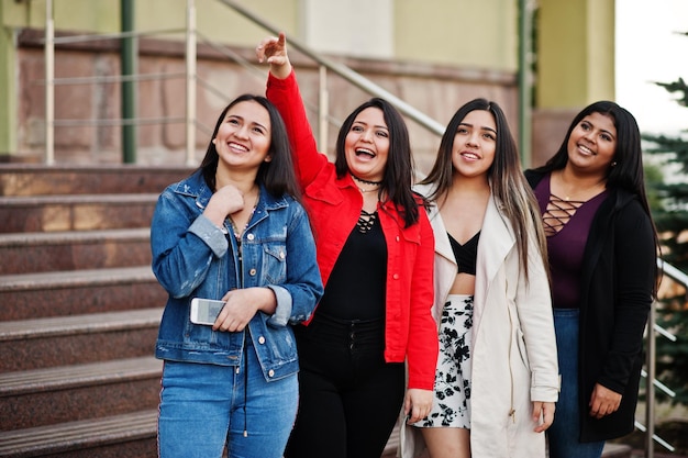 Group of four happy and pretty latino girls from Ecuador posed at street