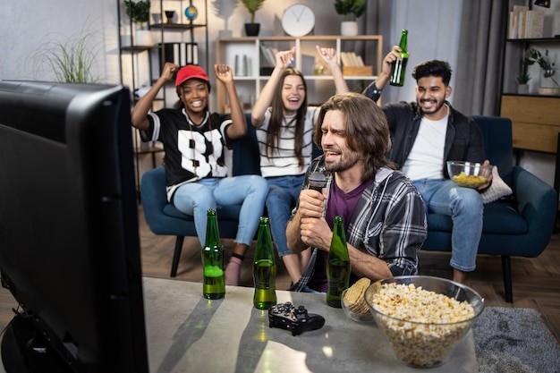 Group of four multicultural people singing karaoke at home