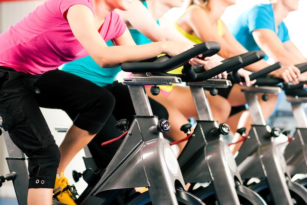 Group of four people spinning in the gym, exercising their legs doing cardio training