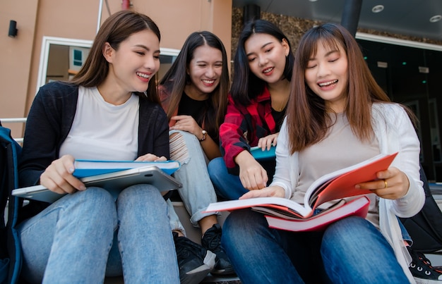 Group of four young attractive asian girls college students studying together in university campus outdoor. Concept for education, friendship and college students life.