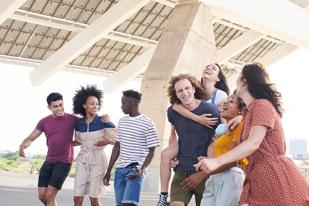 Group of friendly multiethnic friends having fun young students hugging outside the university