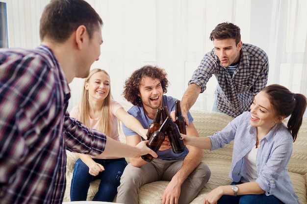 A group of friends are clinking bottles at a meeting in the room