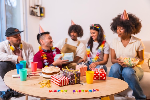 Group of friends at a birthday party on the sofa at home smiling delivering gifts