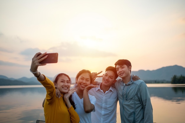 Group of Friends camping together and using Smart phone selfie while vacation