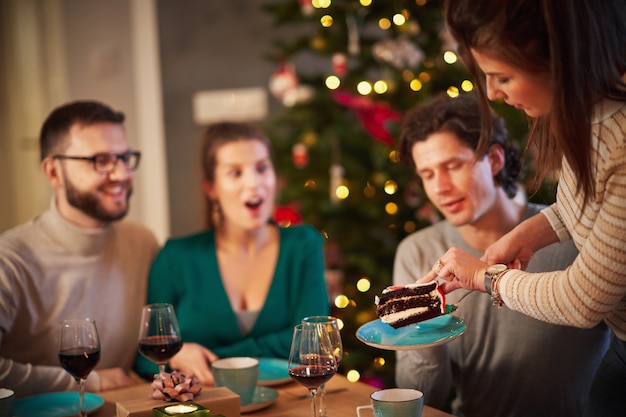 group of friends celebrating Christmas at home enjoying x-mass cake