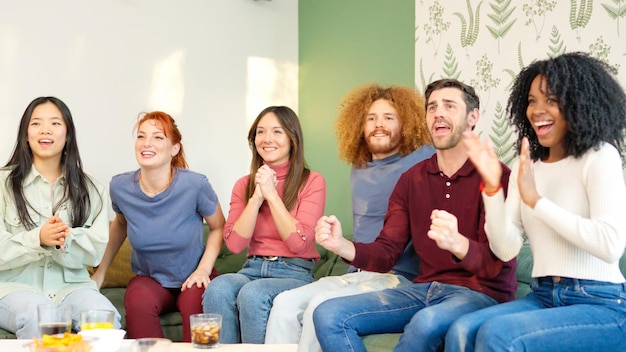 Group of friends celebrating something they are watching on tv