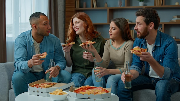 Group of friends colleagues eat pizza talk happy diverse women and men drink beer celebrate event