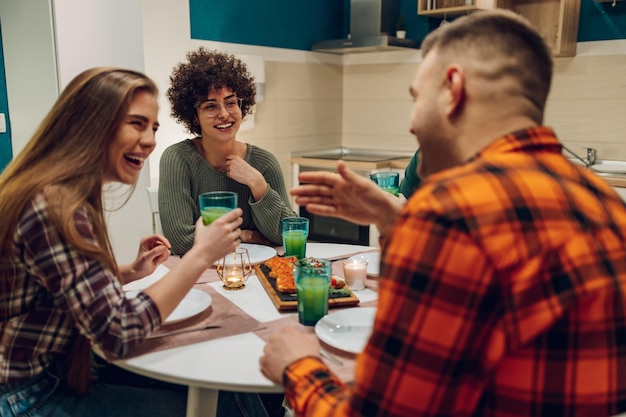 Group of friends enjoying dinner while sitting at the kitchen table together