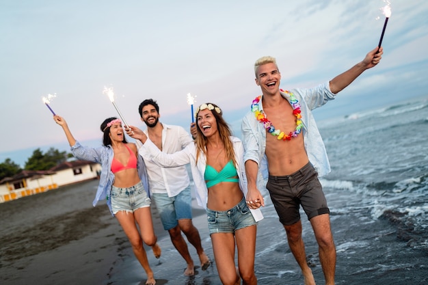 Group of friends having fun on the beach under sunset sunlight.