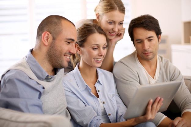 Group of friends at home using tablet in couch