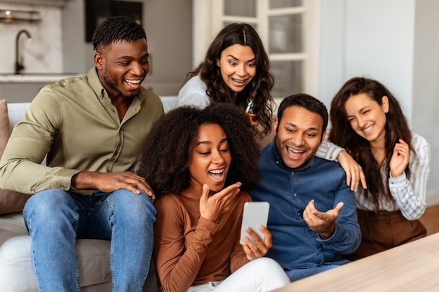 Group of friends laughing with smartphone at home