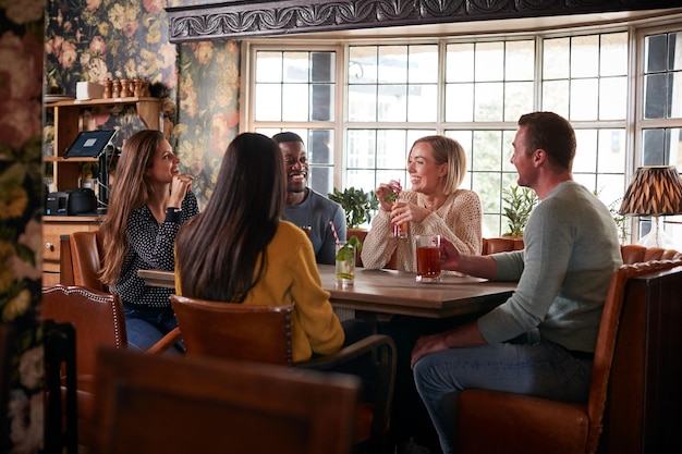 Group Of Friends Meeting For Lunchtime Drinks In Traditional English Pub