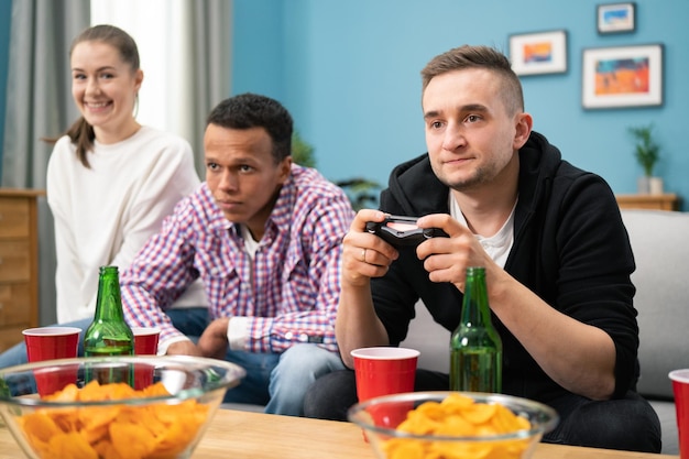 Group of friends play video games together at home having fun a focused man competes with a friend