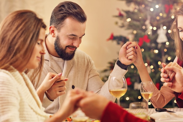 group of friends praying over Christmas table