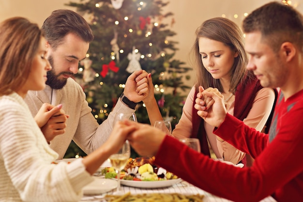 group of friends praying over Christmas table