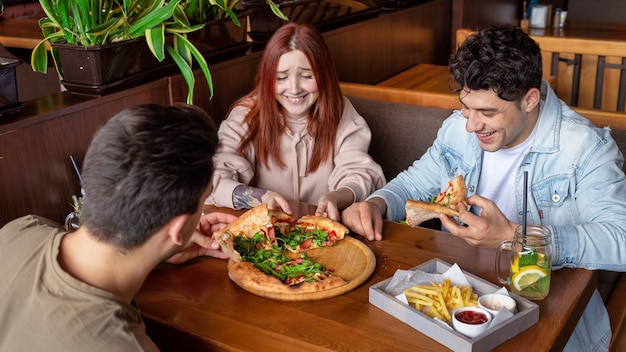 A group of friends resting in a pub. Eating, drinking, food on the table. Friendship